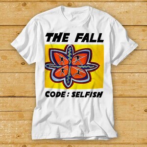 May include: White t-shirt featuring a yellow and orange graphic of a stylised flower with the text "THE FALL" and "CODE: SELFISH" printed on the front.