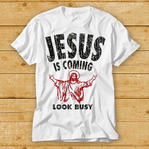 May include: White t-shirt with a black and red graphic print. The graphic features a silhouette of Jesus with the text "JESUS IS COMING LOOK BUSY".