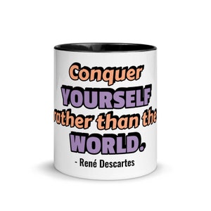 以下が含まれることがあります： 黒い縁取りのある白いセラミック製のコーヒーカップ。カップには、「自分自身を征服せよ、世界を征服するのではなく。 - ルネ・デカルト」という黒、オレンジ、紫のテキストで引用が書かれている。