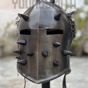May include: A dark metal helmet with multiple black spikes and chainmail detail. The helmet has two eye slits and a leather strap. The word "YOUNGSMITH" is printed at the top of the image.