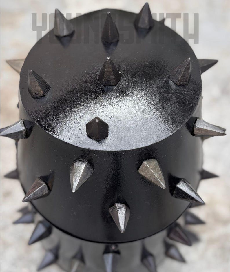 May include: A black, spiked metal object with a rounded top and a cylindrical base. The spikes are various sizes and shapes, some with a metallic sheen. The text "YUNSMITH" is visible at the top.