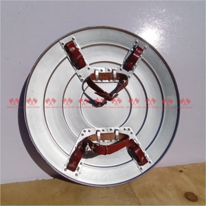 May include: A silver metal shield with a red leather strap and rivets. The shield is round and has a raised center.