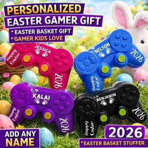 May include: Four colorful game controllers, personalized with names and the year 2026, are displayed on grass with Easter eggs and a bunny. The controllers are pink, blue, purple, and black, with the words "Happy Easter" on them.