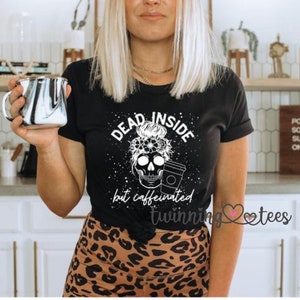 May include: Black t-shirt with a white skull graphic and the text "Dead Inside but caffeinated" with a coffee cup in the skull's hand. The text "Twinning Tees" is visible in the bottom right corner.