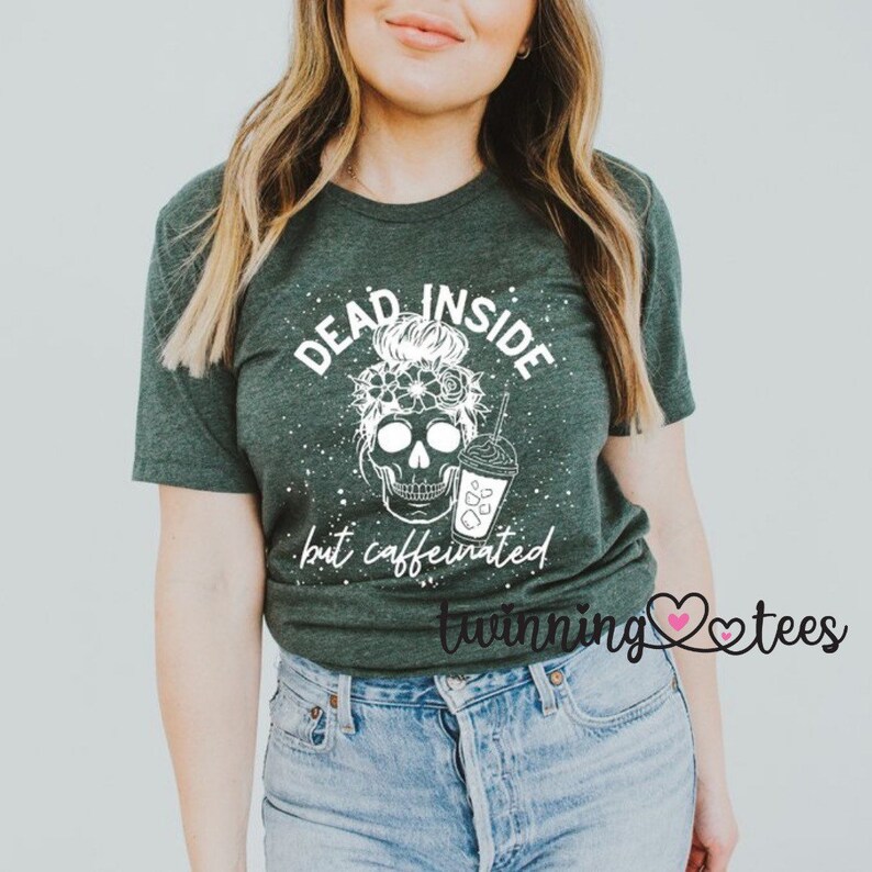 May include: A green t-shirt with a white skull graphic and the text "Dead Inside but caffeinated". The skull is wearing a flower crown and holding a coffee cup.