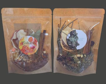 May include: Two brown kraft paper pouches containing potpourri. The left pouch features a label with the text Autumn and images of pumpkins and apples. The right pouch features a label with the text Winter and images of pine branches and citrus slices.