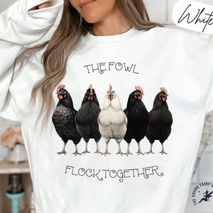 Puede incluir: Sudadera blanca con una ilustración en blanco y negro de cinco pollos y el texto "The Fowl Flock Together".