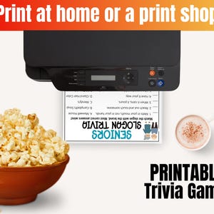 K&ouml;nnte beinhalten: Ein schwarzer Drucker gibt ein Seniors Slogan Trivia Spielblatt aus, begleitet von einer braunen Sch&uuml;ssel mit Popcorn und einer wei&szlig;en Tasse mit einem hellbraunen Getr&auml;nk. Der Text lautet Print at home or a print shop und Printable Trivia Game.