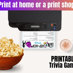 May include: A black printer printing a printable Hip-Hop Trivia game. A bowl of popcorn and a cup of coffee are on the left and right. The text at the top says "Print at home or a print shop". The text at the bottom says "Printable Trivia Game".