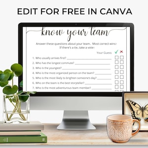 May include: A computer monitor displaying a Know Your Team game template with seven questions and checkboxes. The screen text reads Edit for Free in Canva. The monitor is placed near a glass vase with green leaves, a stack of books, a patterned mug, and a framed butterfly.
