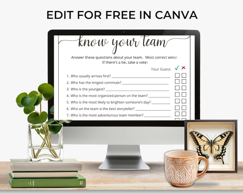 May include: A computer monitor displaying a Know Your Team game template with seven questions and checkboxes. The screen text reads Edit for Free in Canva. The monitor is placed near a glass vase with green leaves, a stack of books, a patterned mug, and a framed butterfly.