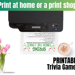 Puede incluir: Una impresora negra imprimiendo una hoja de juego de trivia con el texto "Finish the Lyrics" y "Spring". Un jarr&oacute;n de cristal con tulipanes rosas y una taza de caf&eacute; tambi&eacute;n est&aacute;n en la imagen. El texto "Print at home or a print shop" est&aacute; en la parte superior.