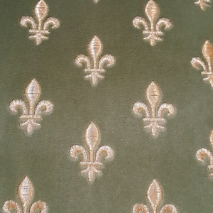 May include: A green fabric with a repeating pattern of gold fleur-de-lis.