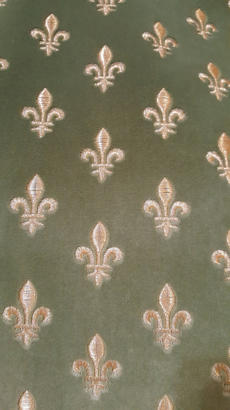 May include: A green fabric with a repeating pattern of gold fleur-de-lis.