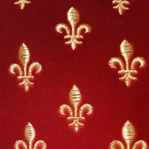 May include: Red velvet fabric with a repeating pattern of gold embroidered fleurs-de-lis.