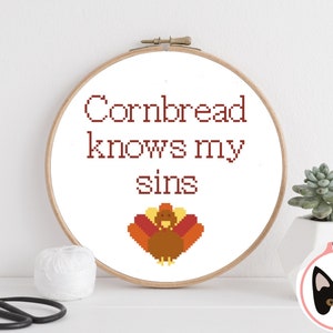 May include: A white embroidery hoop with the text "Cornbread knows my sins" in brown lettering. A pixelated image of a turkey is below the text.