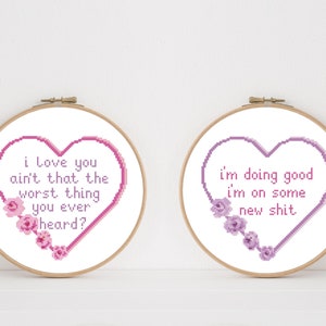 Puede incluir: Dos aros de bordado con corazones rosas y morados y diseños florales. El texto en el corazón rosa dice "i love you ain't that the worst thing you ever heard?" El texto en el corazón morado dice "i'm doing good i'm on some new shit."