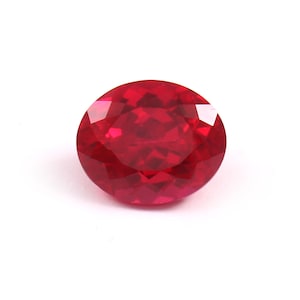 May include: A round-cut ruby gemstone with multiple facets. The gem is a deep red colour, with facets that reflect light. The ruby is set against a plain white background, highlighting its brilliance and clarity. Suitable for jewellery.