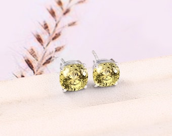 May include: A pair of silver stud earrings with round, yellow gemstones.