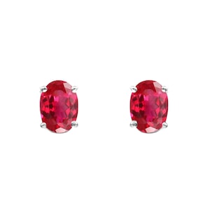 May include: A pair of silver stud earrings with oval-shaped red gemstones.