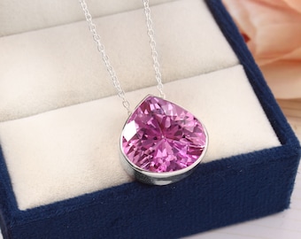 May include: A silver chain necklace with a large pink pear-shaped gemstone pendant.