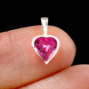 May include: A silver pendant featuring a pink heart-shaped gemstone.