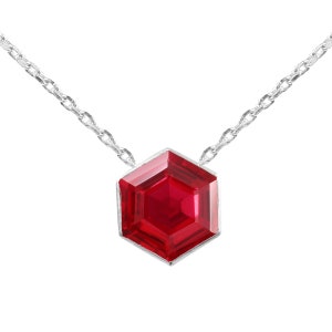 May include: A silver chain necklace with a red hexagonal pendant.