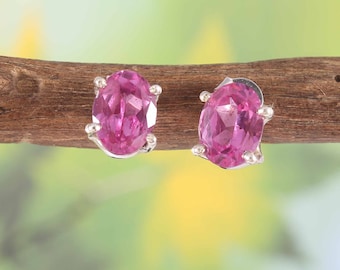 May include: A pair of silver stud earrings with oval-shaped pink gemstones.