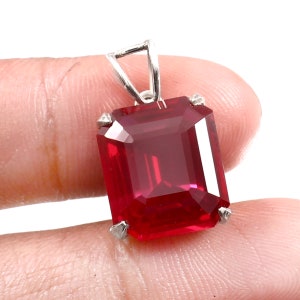 Puede incluir: Un colgante de piedra preciosa roja con engaste de plata. La piedra preciosa está tallada en forma de esmeralda.