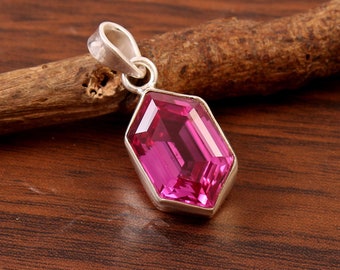 May include: A silver pendant with a large, faceted, pink gemstone. The pendant is shaped like a hexagon and has a simple bail.