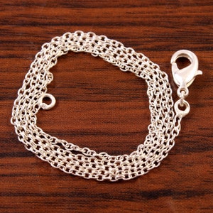 Puede incluir: Un collar de cadena de plata con cierre de mosquet&oacute;n. La cadena est&aacute; hecha de m&uacute;ltiples hebras de peque&ntilde;os c&iacute;rculos unidos.