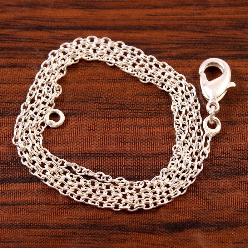 Puede incluir: Un collar de cadena de plata con cierre de mosquet&oacute;n. La cadena est&aacute; hecha de m&uacute;ltiples hebras de peque&ntilde;os c&iacute;rculos unidos.