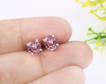 May include: A pair of silver stud earrings with round, pink gemstones.