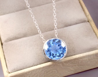 May include: A silver chain necklace with a round blue gemstone pendant.