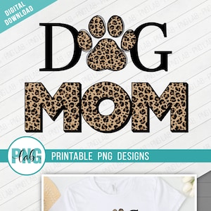 以下が含まれることがあります： 「DOG MOM」という文字の黒いアウトラインが描かれた白いTシャツ。 「O」の真ん中にヒョウ柄の足跡があります。