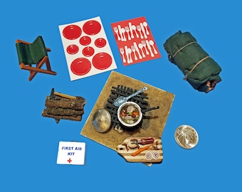 L'ensemble de camping miniature à l'échelle 1:12 comprend un feu de camp Camper's Stew, un tas de bois, un sac de couchage, un tabouret de camping, une vaisselle de pique-nique et une trousse de premiers soins