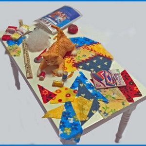 Dollhouse Miniature Quilting Table. Fabric, yardstick, tape measure, scissors, pin cushion, thread, sewing book, Polyfill, cat. 1:12 Scale