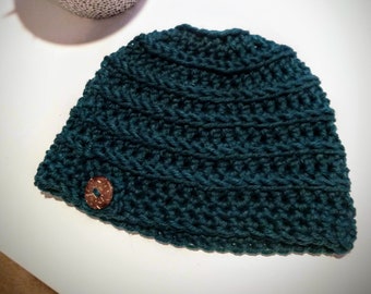 May include: A teal blue crocheted beanie with a brown button.