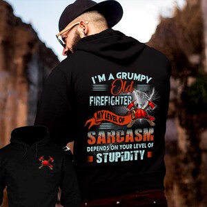 May include: Black hoodie with the text "I'M A GRUMPY Old FIREFIGHTER" and "MY LEVEL OF SARCASM DEPENDS ON YOUR LEVEL OF STUPIDITY". The design includes a firefighter's helmet and crossed axes with lightning bolts.