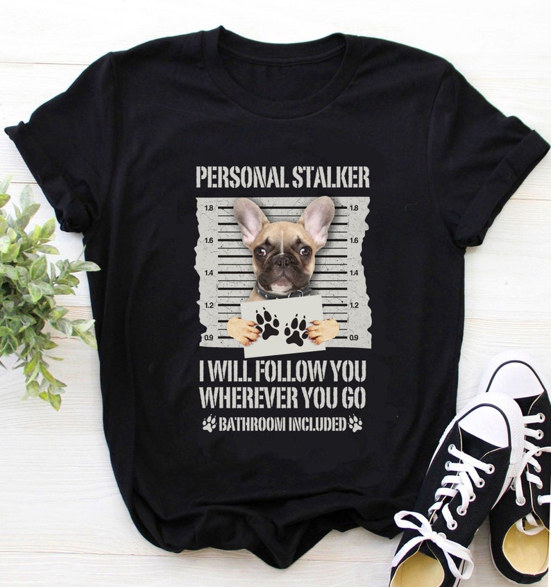 May include: Black t-shirt with a white graphic of a French bulldog holding a sign that says "I will follow you wherever you go, bathroom included".