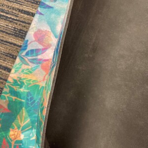 May include: A yoga mat with a colorful floral pattern on one side and a black non-slip surface on the other side.