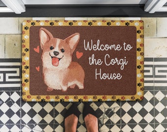 May include: A brown doormat with a yellow border and paw prints. A cartoon corgi dog is in the centre of the mat with the text "Welcome to the Corgi House".