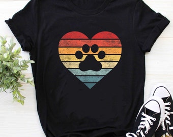 May include: Black t-shirt with a vintage-style rainbow heart design featuring a paw print in the center.