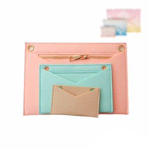 May include: Three felt pouches with zipper closures. The largest pouch is pink, the middle pouch is light blue, and the smallest pouch is beige.