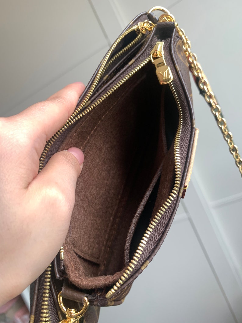 May include: A brown and gold chain strap purse with a brown fabric interior and two zippered compartments. The purse is open and the interior is visible.