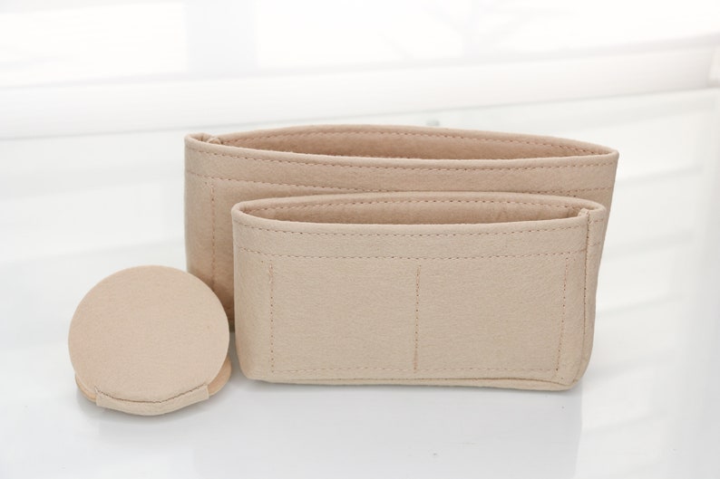 May include: Three beige felt bag organizers with different sizes and compartments. The largest organizer has three compartments, the medium organizer has two compartments, and the smallest organizer is round.