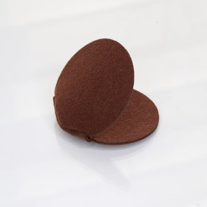 May include: A brown felt circle folded in half, creating a rounded shape. The felt is soft and textured.