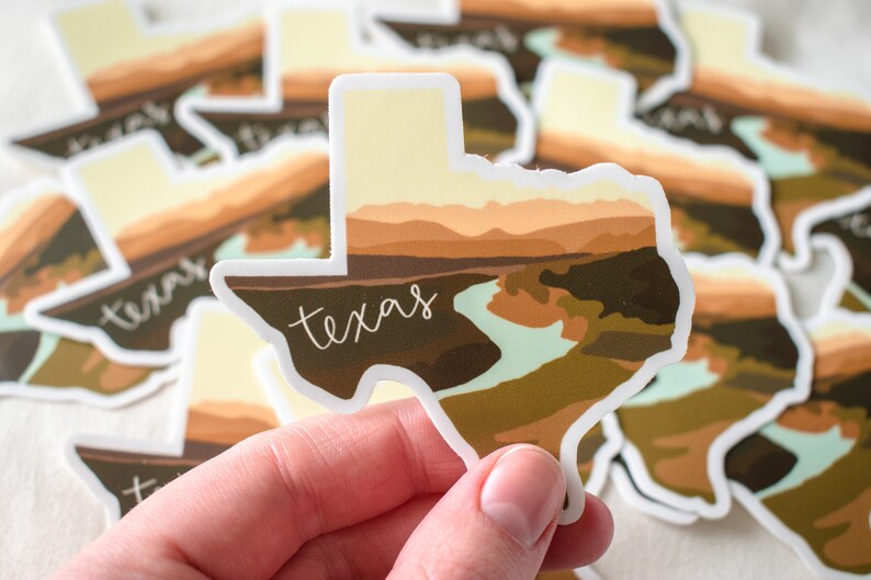 Puede incluir: Una colecci&oacute;n de pegatinas con la forma del estado de Texas. Cada pegatina presenta un dise&ntilde;o de paisaje en tonos marrones, beige y verdes, con la palabra "texas" en escritura blanca. Las pegatinas tienen un borde blanco.