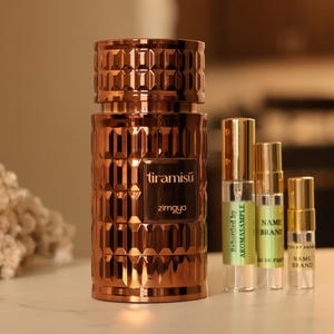 May include: A gold bottle of perfume with the name "tiramisu" and the brand "zimgua" printed on the label. The bottle is surrounded by four smaller bottles of perfume.