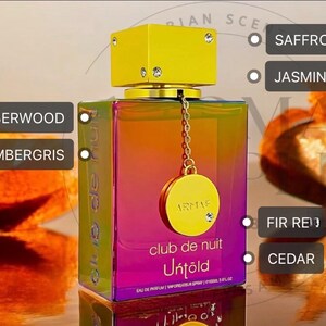 May include: A rectangular perfume bottle with a gradient of colors, from purple to orange, and a gold cap. The bottle has a gold charm with a chain. The scent notes include saffron, jasmine, fir red, and cedar.